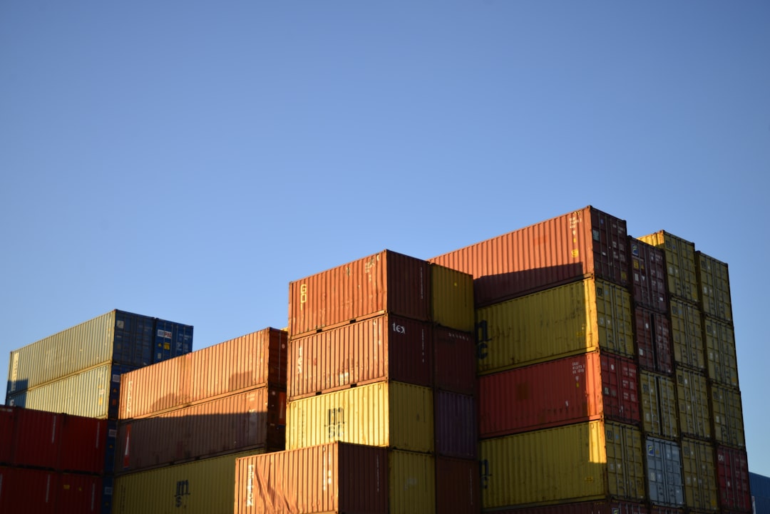 Mastering the First Impression: Your intriguing post title goes here Colourful shipping containers stacked in side light with blue sky background.